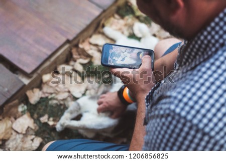 Taking a photo of a cat with a cellphone.
