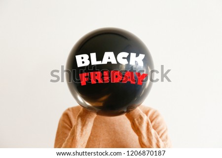Young woman covering her head with ballon, black friday text. Fourth Friday of November, beginning of Christmas shopping season since 1952. Copy space, close up, top view, flat lay, background.