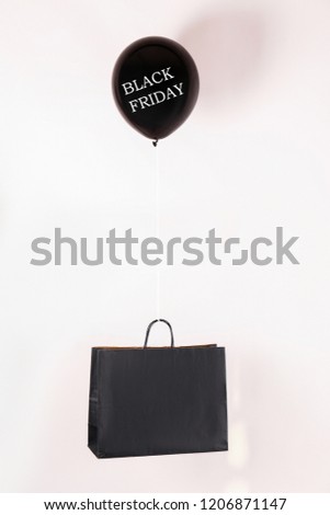 Black friday text on flying balloon lifting shopping bag. Fourth Friday of November, beginning of Christmas shopping season since 1952. Copy space, close up, top view, flat lay, background.