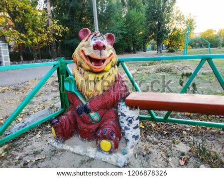 Wooden sculpture on the playground. Smiling bear.