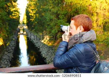 Beautiful girl taking pictures of autumn landscape