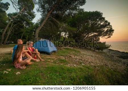 Family looking at sunset close to tent on mediterranean.