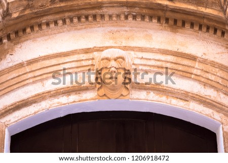 Gothic detail. Young woman portrait at the entrance of a 200 years old building in Ciutadella town, Menorca (Spain)