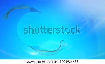 Horizontal orientation intraocular lens on blue background with light flare
