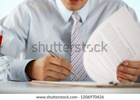 Hand of businessman in suit filling and signing with silver pen partnership agreement form clipped to pad closeup. Management training course some important document team leader ambition concept