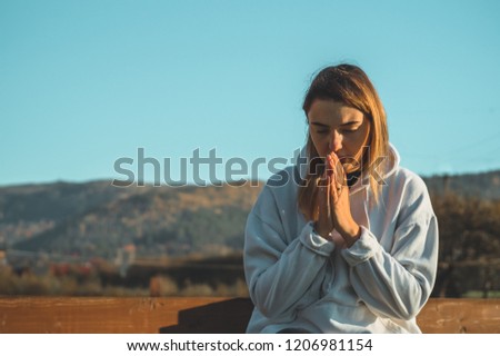 In the morning Girl closed her eyes, praying outdoors, Hands folded in prayer concept for faith, spirituality and religion. Peace, hope, dreams concept.