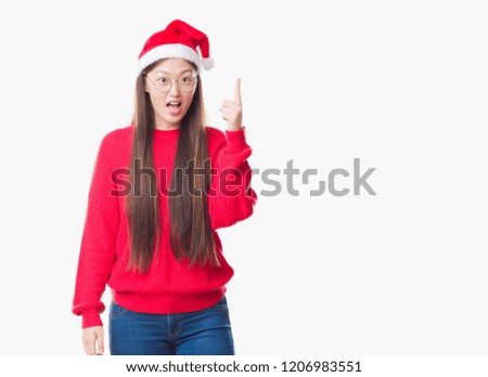 Young Chinese woman over isolated background wearing christmas hat pointing finger up with successful idea. Exited and happy. Number one.
