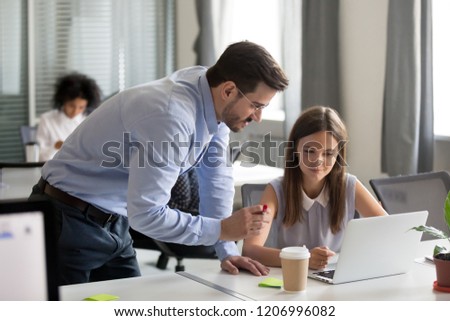 Middle-aged executive manager boss mentor teacher explaining online work to young focused intern looking at computer screen in office teaching training new worker instructing about software on laptop Royalty-Free Stock Photo #1206996082