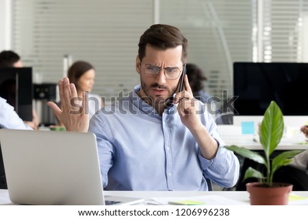 Angry business man talking on phone disputing looking at laptop, stressed frustrated office worker arguing by mobile solving online computer problem with technical support complaining on bad service Royalty-Free Stock Photo #1206996238