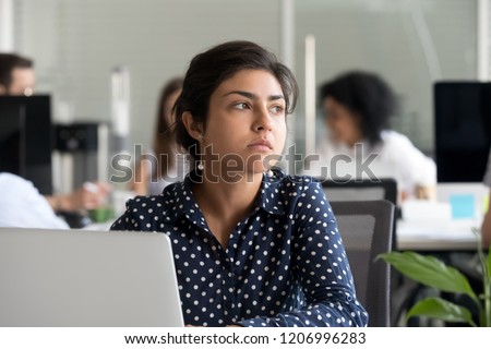 Thoughtful indian business woman looking away feeling bored pensive thinking of problem solution in office with laptop, serious hindu employee searching new ideas at work unmotivated about dull job Royalty-Free Stock Photo #1206996283
