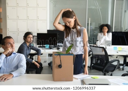 Upset female employee packing belongings in box, frustrated stressed girl getting fired from job ready to leave on last day at work, sad office worker desperate about unfair dismissal losing job Royalty-Free Stock Photo #1206996337