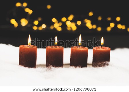 Christmas and advent candle still life series in snow with silent black night background and bokeh lights