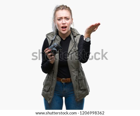 Young blonde woman taking pictures using vintage camera over isolated background annoyed and frustrated shouting with anger, crazy and yelling with raised hand, anger concept