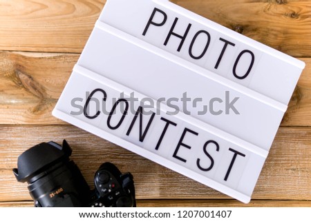 Text "photo contest"  written on white slate with camera on wooden background. Suitable for advertising Royalty-Free Stock Photo #1207001407