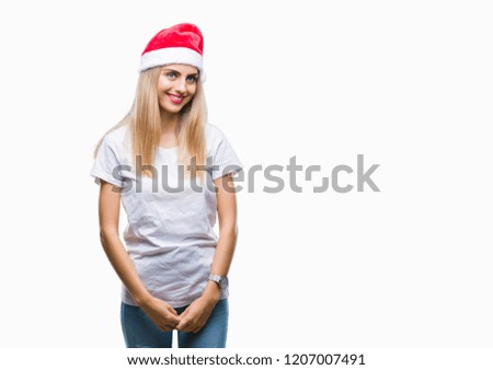 Young beautiful blonde woman christmas hat over isolated background looking away to side with smile on face, natural expression. Laughing confident.