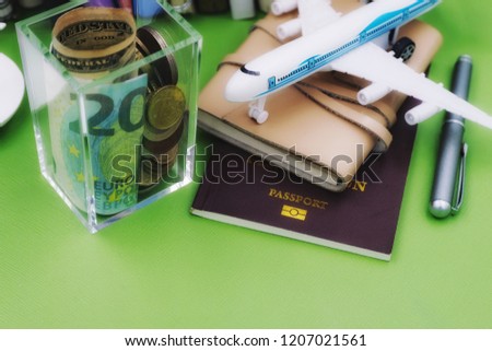 Money and aircraft figurine on a passport with green background
