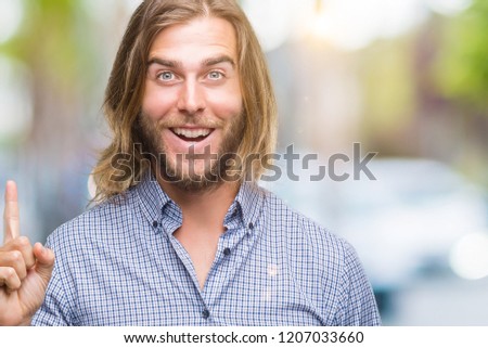 Young handsome man with long hair over isolated background pointing finger up with successful idea. Exited and happy. Number one.