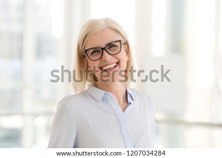 Portrait of smiling middle-aged businesswoman in glasses look in camera making headshot picture, happy mature female employee pose for picture in office, confident woman excited for new opportunities