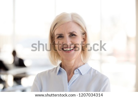 Portrait of happy mature businesswoman posing in modern light office, headshot of smiling middle-aged female employee look in camera making professional business picture, woman photoshoot in boardroom