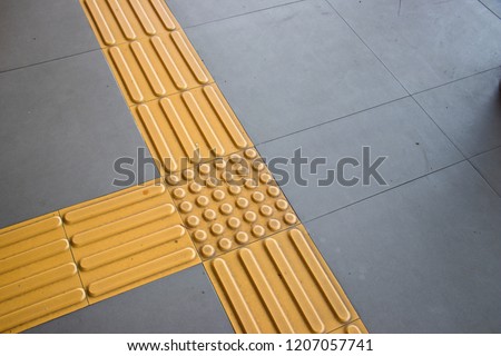 Bright yellow tactile paving 
for the visually impaired on the sidewalk.