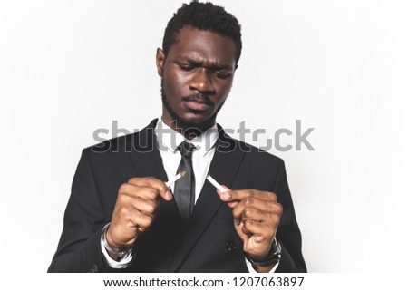 man breaks a cigarette, quits smoking. Portrait of a young African American in a business suit. emotions on the face. isolated on white background, free space for text