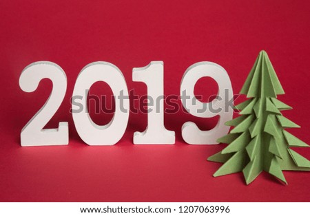 green origami paper tree and white symbol of 2019, on a red background, free space for text, minimalism. Happy New Year 2019 year, calendar