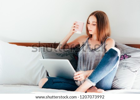 Woman with laptop working on the bed at the hotel room.