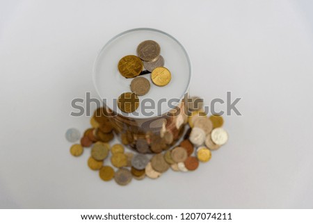 Studio photo of a decorative piggy bank with scattered cash coins on a white background