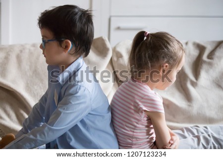 Offended little preschool siblings after quarrel, punishment sitting together on sofa in living room at home dont look at each other. Sulky sister and brother have conflict feeling frustrated unhappy Royalty-Free Stock Photo #1207123234