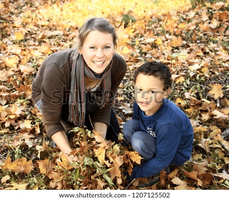 mother and son having fun with autumn leaves stock photo
