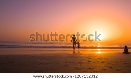 Silhouette of father with two children in the beach at sunset