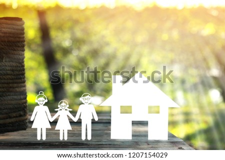 A family and home model with paper art put on the wood on nature bokeh in the public park, The saving money for house or real estate owner in the future concept.
