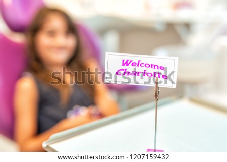 Welcome sign in dentist room for children, blurred girl in background