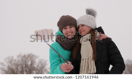 Mom and daughter do selphi Winter in snow. Carefree Teens Celebrate Christmas Outdoors, They Pose For Fun Selfies