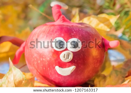 Children crafts pig from red apple and plasticine on yellow autumn leaves