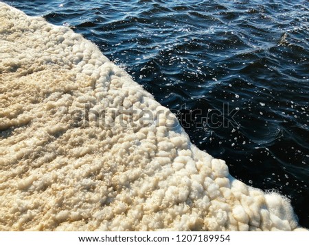 Dirty foam on the lake water, top view. 