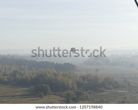 Balloon flying in the sky. Colorful hot air balloon flying over rock landscape in blue sky. Morning balloon flight over the fields and forests.