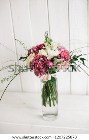 flowers in a glass vase on a white wooden background