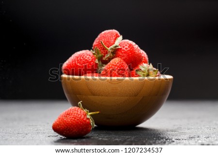 Photo close-up of ripe strawberry in wooden cup on black background