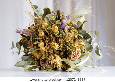 Close up of wedding bouquet of dried flowers lying on a white table