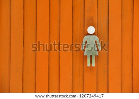 Female figure is made of stainless steel.
On a wooden wall means a female toilet.