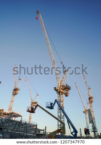 Big white tower cranes above buildings under construction against blue sky. Background image of construction close-up with copy space. Build of city.