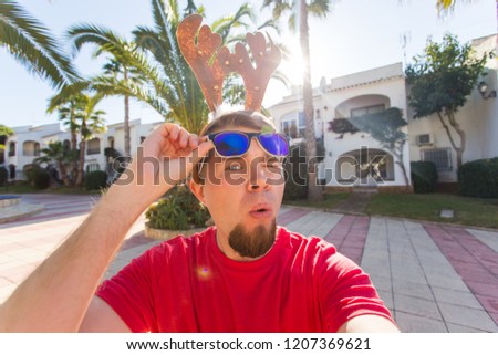 People, christmas and holidays concept - young man in deer horns taking selfie outdoors