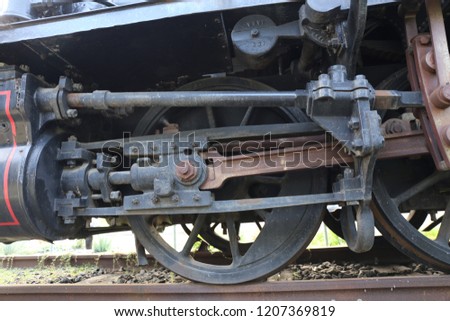 Close up exterior view of iron wheels of an ancient french locomotive. Detail of an old machinery used for transportation by train. Vintage industrial picture with steel rails. Abstract retro image.