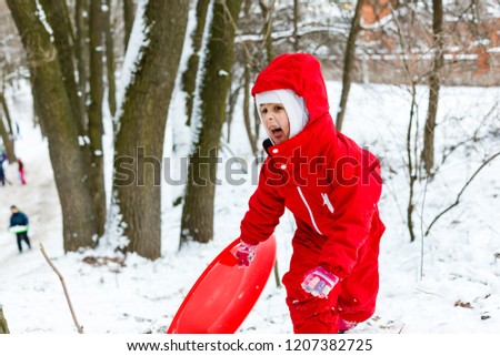Little girl in red going to ride ice slide