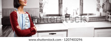 Waitress standing with arms crossed against white background against view of kitchen