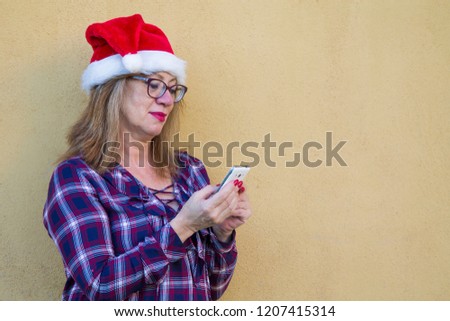 mature woman with santa hat using the mobile phone