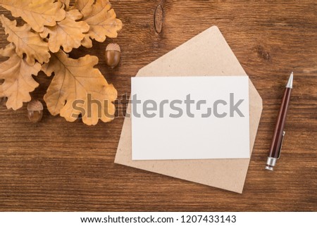  Envelope with a pen and autumn leaves on wooden background