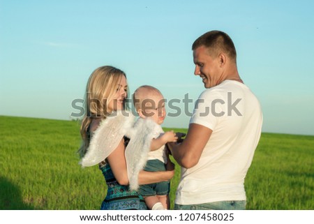 Happy family in a green meadow. A child with angel wings. The concept of family and happiness.