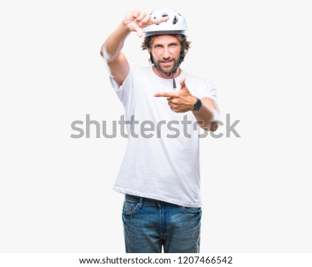 Handsome hispanic cyclist man wearing safety helmet over isolated background smiling making frame with hands and fingers with happy face. Creativity and photography concept.